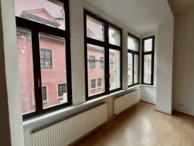 Heller Raum mit Fensterfront und Ausblick auf Nachbargebäude